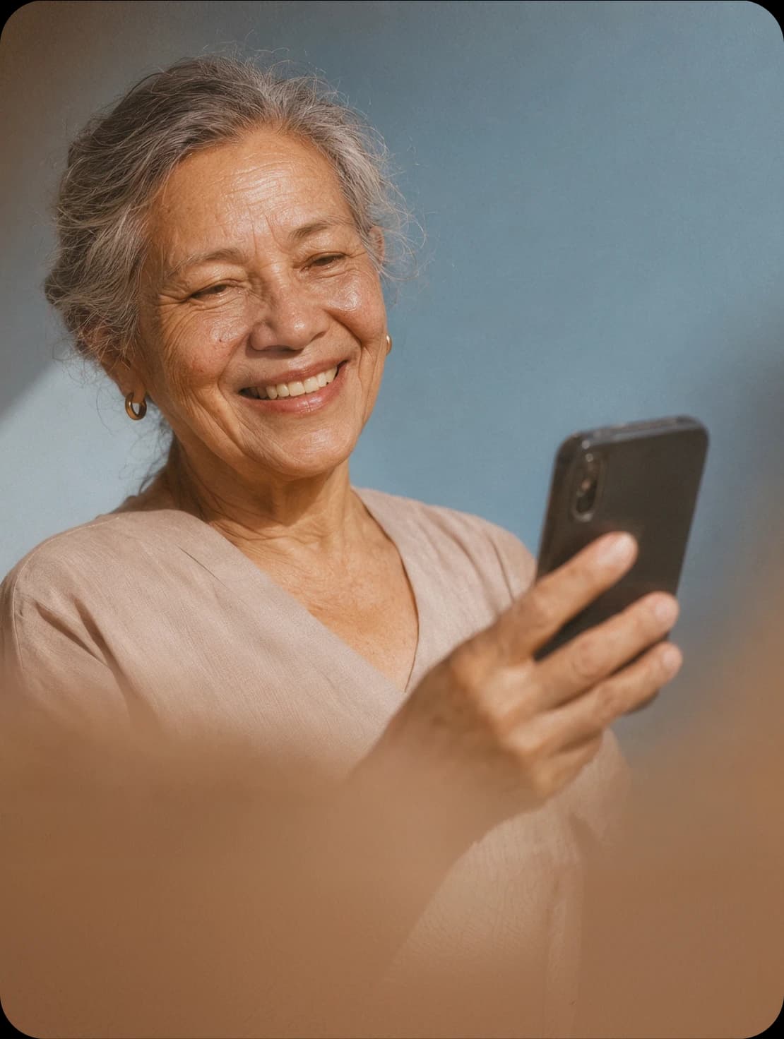 An older woman smiling at a text on her phone